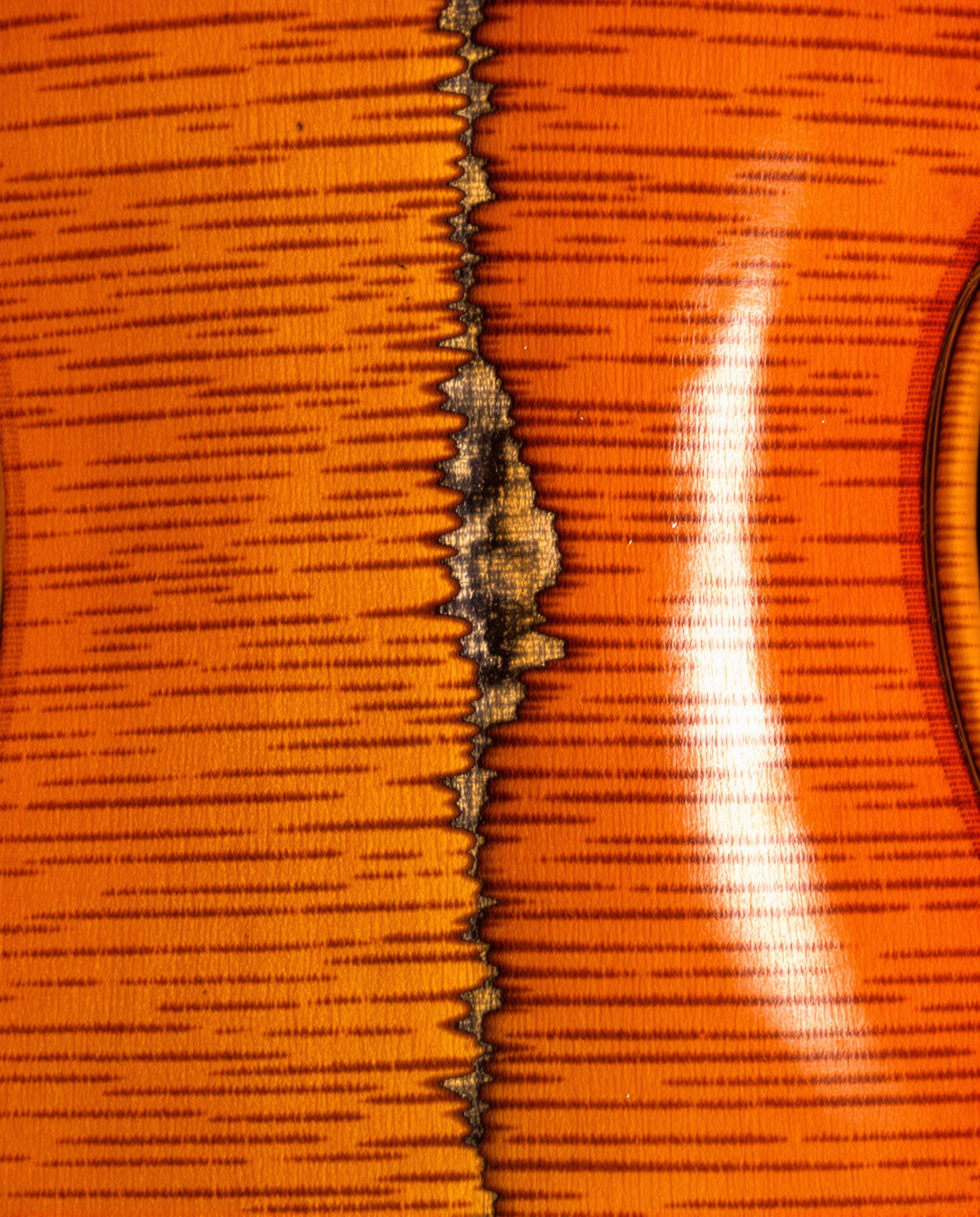Gros plan sur le fond d'un ancien violon de Crémone montrant des ondes imparfaites et quelques irrégularités naturelles du bois. Exemple vivant du travail avec la matière brute.