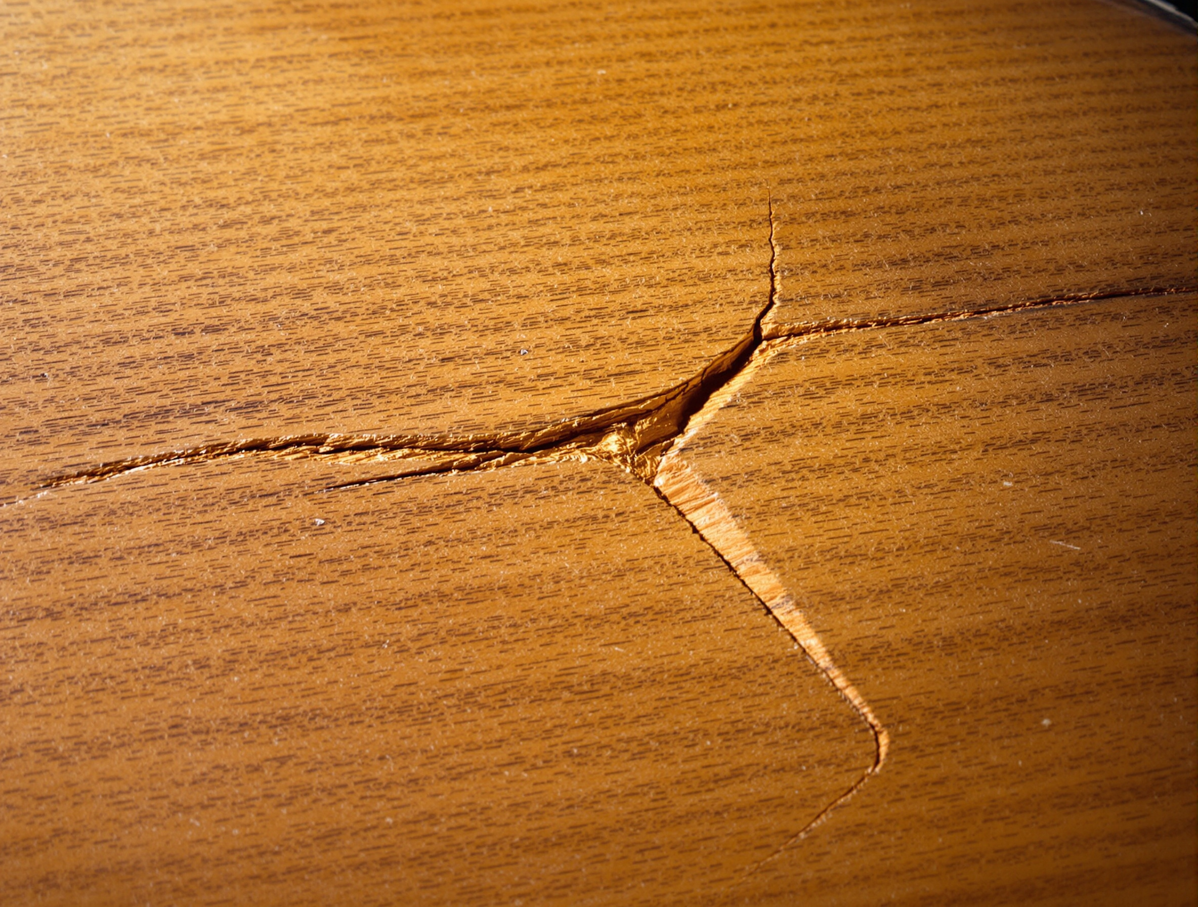 Macro d'une fissure fine sur la table d'harmonie d'une vieille guitare éclairée en lumière rasante