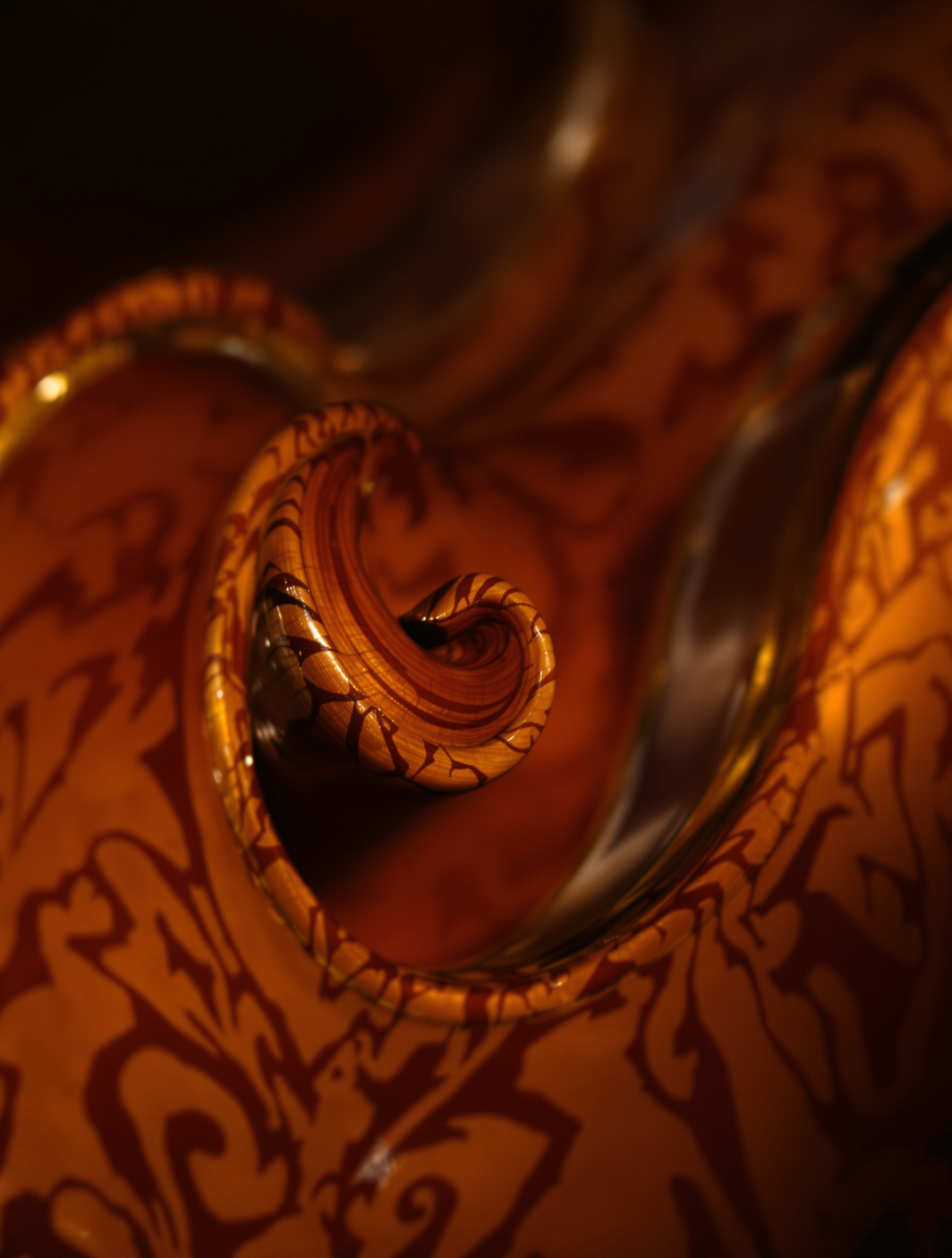 Volute finement sculptée d’un violon en érable ondé sous éclairage latéral – illustration du savoir-faire artisanal et des matériaux d’exception.
